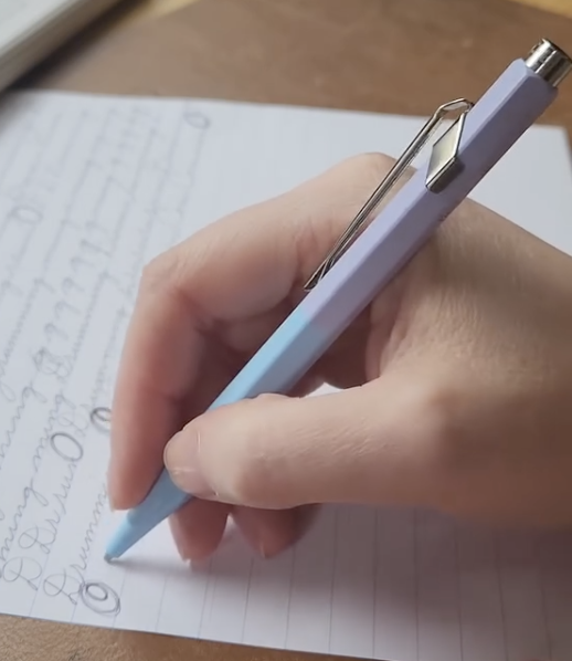 The pen held for writing, seen from the side